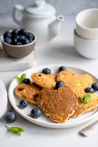 Pancakesheart en forme de myrtilles fraîches Petit-déjeuner matinal délicieuses crêpes végétaliennes Arrière-plan lumineux