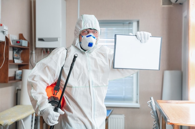 Photo pandémie de coronavirus. un désinfectant en tenue de protection et masque vaporise des désinfectants dans la maison ou au bureau. protection contre la maladie covid-19. prévention de la propagation du virus de la pneumonie avec les surfaces.