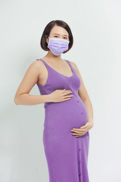 Pandémie de coronavirus, jeune femme enceinte portant un masque médical de protection tient sur le ventre