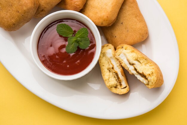 Paneer pakoras ou Bhajji sont des cubes de fromage cottage épicé enrobés de farine de gramme ou de pâte à besan. Servi avec du ketchup à la tomate dans une assiette sur fond coloré ou en bois. Mise au point sélective