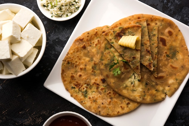 Paneer Paratha farci au beurre fondant, servi avec des cubes de fromage cottage frais et du ketchup aux tomates. Mise au point sélective