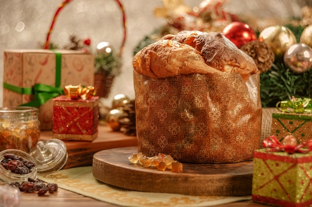 Panettone, raisins secs et cubes de fruits confits sur une planche à découper en bois avec des ornements de Noël