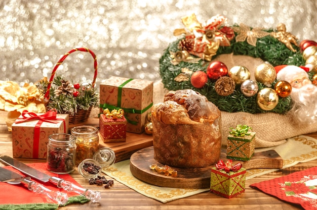 Panettone, raisins secs et cubes de fruits confits sur une planche à découper en bois avec des ornements de Noël