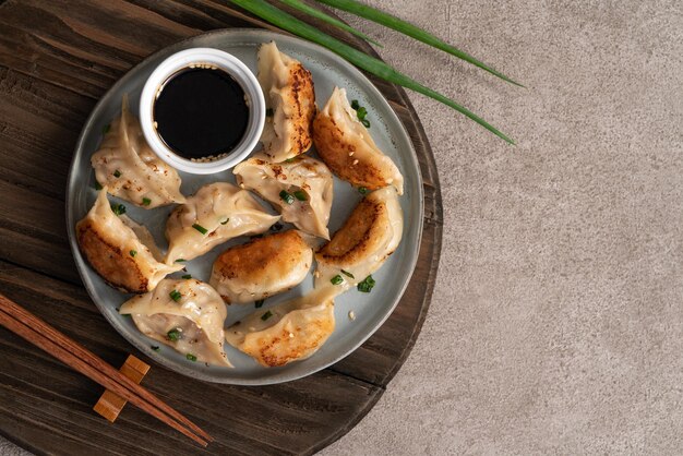 Panfried gyoza dumpling jiaozi dans une assiette avec de la sauce soja sur fond de table gris