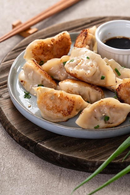 Panfried gyoza dumpling jiaozi dans une assiette avec de la sauce soja sur fond de table gris