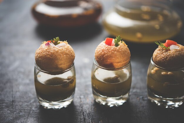 Photo pani puri est un élément de chat indien au bord de la route - quatre puris farcis conservés dans de petits verres remplis d'eau à la menthe