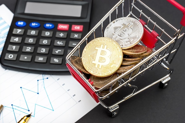 Panier d'achat avec calculateur de bitcoins et graphiques d'entreprise sur fond noir Concept commercial et financier