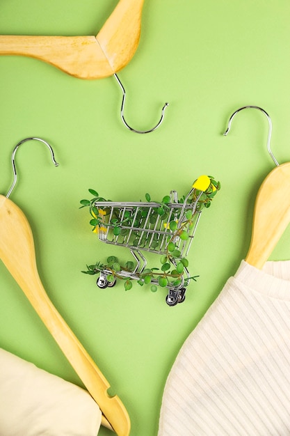 Panier d'achat entrelacé de plantes sur fond vert parmi des cintres style de vie écologique durable