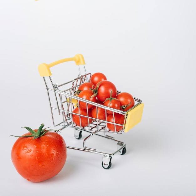 Photo panier d'achat rempli de tomates rouges fraîches sur fond blanc