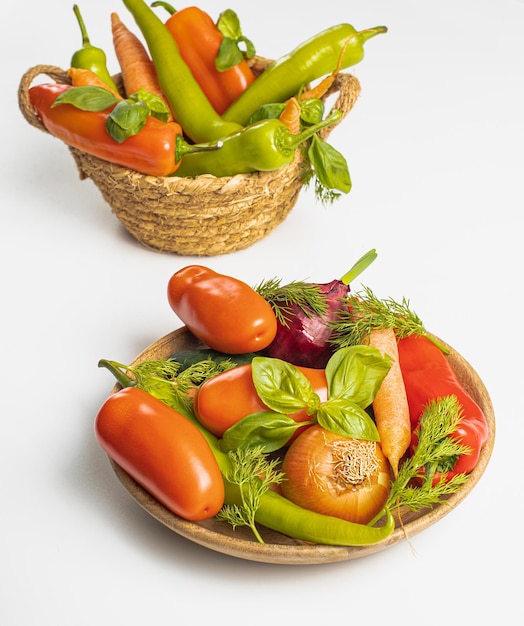 Panier et assiette en bois avec des légumes frais sur la vue de dessus de fond blanc