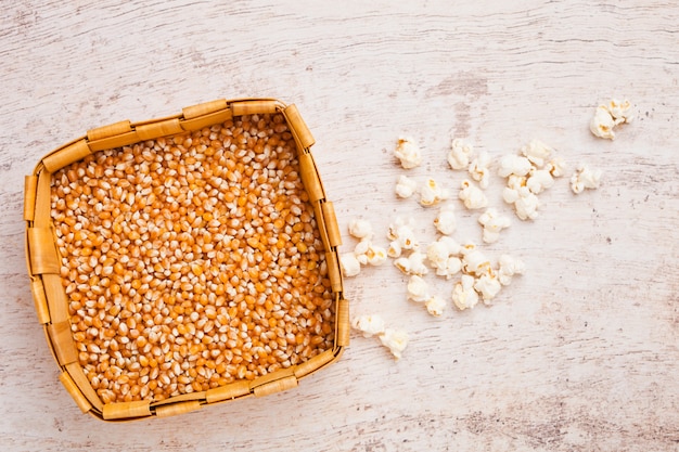 Panier en bambou avec maïs sucré cru et pop-corn sur fond de bois