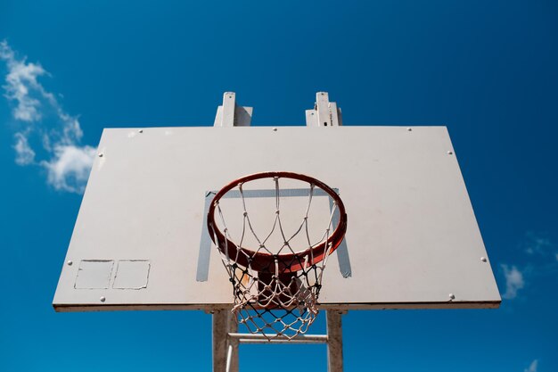 Panier de basket extérieur en journée ensoleillée sur fond de ciel bleu