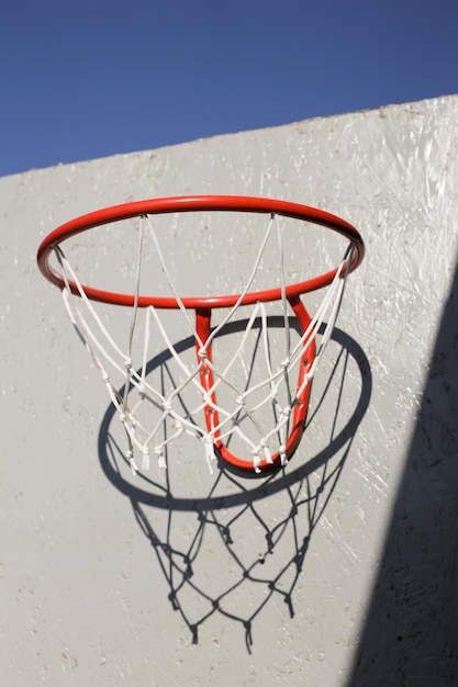 Un panier de basket rouge avec un filet blanc contre un ciel bleu sans nuages