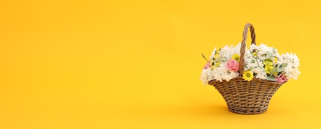 Panier avec de belles fleurs sur fond jaune