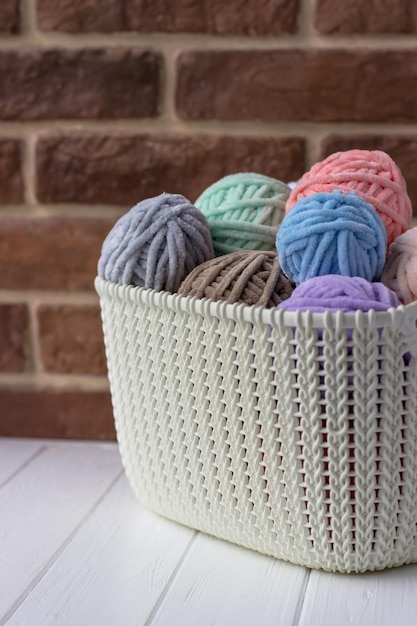 Panier avec bobines de fil en peluche dans des tons pastel Panier de tricoteuse sur un tableau blanc