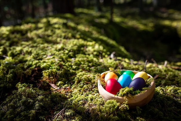 Un panier en bois en forme d'oeuf avec des oeufs colorés dedans