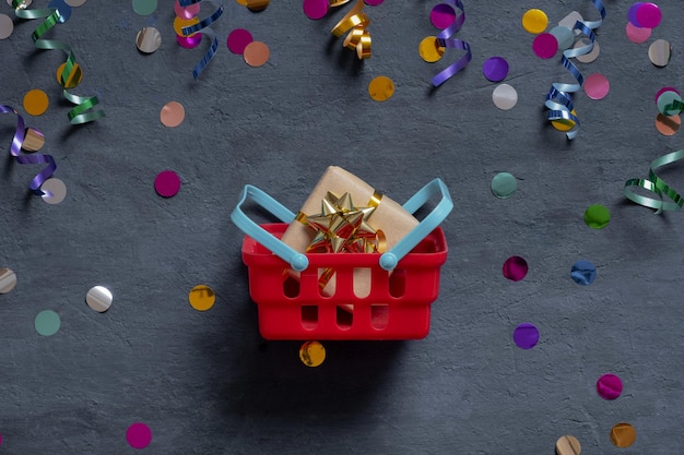 Panier avec boîte-cadeau et guirlandes festives à plat sur fond sombre Vue de dessus