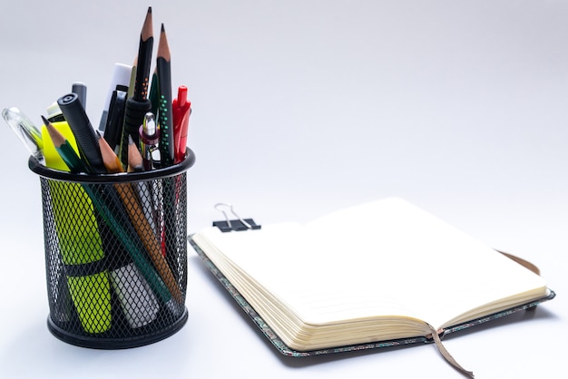 Panier de bureau avec crayons, stylos, marqueurs et un cahier ouvert