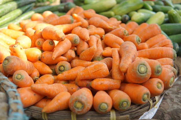 Un panier de carottes avec d'autres légumes dessus