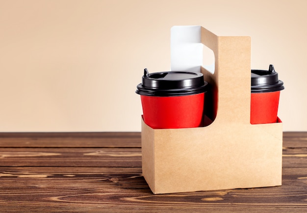 Photo panier en carton avec deux tasses de café pour aller sur une table en bois