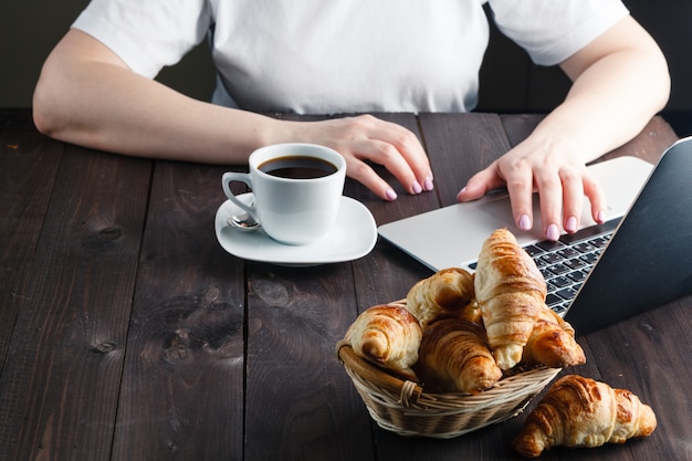 Panier avec de délicieux croissants frais et une tasse de café chaud le matin