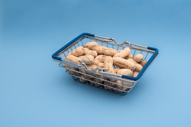 Panier d'épicerie avec des arachides sur une table bleue