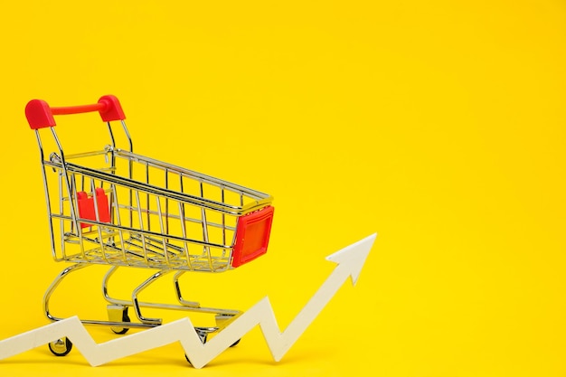 Panier d'épicerie et flèche graphique pointant vers le haut et hausse des prix des marchandises sur fond jaune