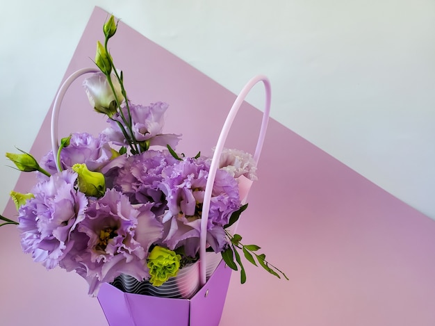 Un panier de fleurs un bouquet d'eustomas sur un fond lilas copyspace