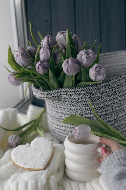 Un panier de fleurs violettes se trouve à côté d'un cookie en forme de cœur.