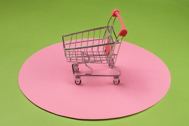 Photo panier sur fond vert avec cercle pastel rose. concept de shopping minimaliste, accro du shopping.