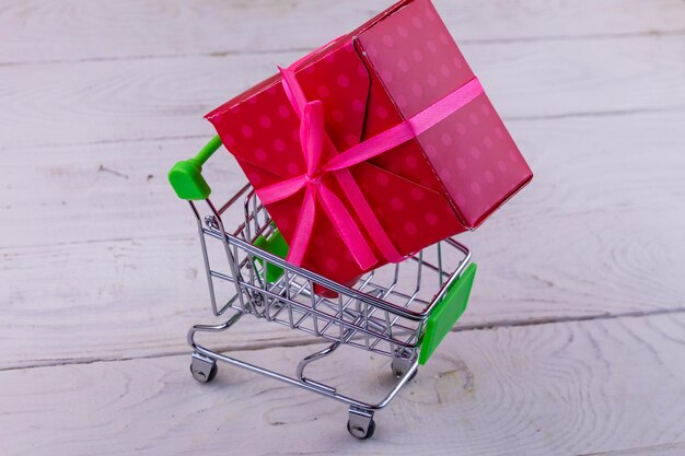 Panier avec grande boîte-cadeau sur fond de bois blanc