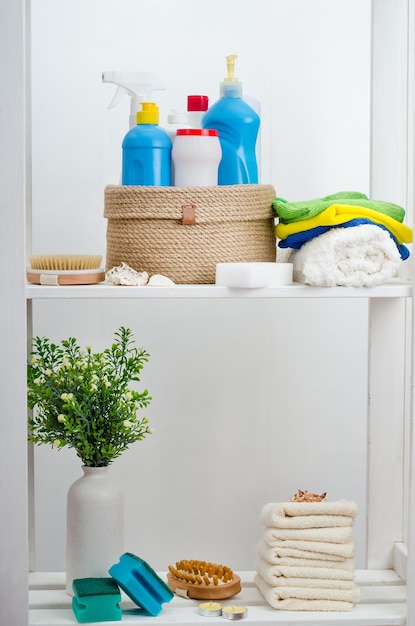 Panier en jute tricoté à la main avec un couvercle avec des détergents et des serviettes dans la salle de bain sur un support en bois blanc