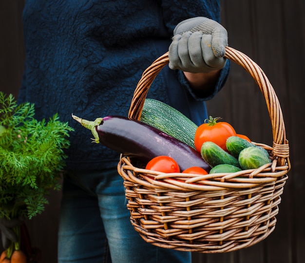 Panier de légumes dans les mains d'un fermier sur un bois.