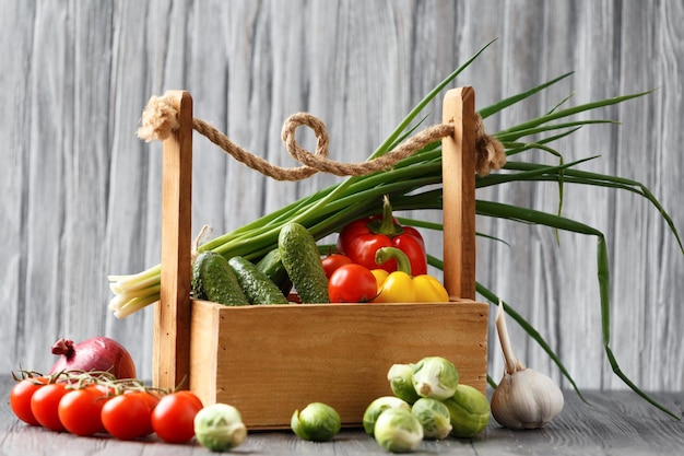 Photo panier de légumes dans les mains sur un fond en bois