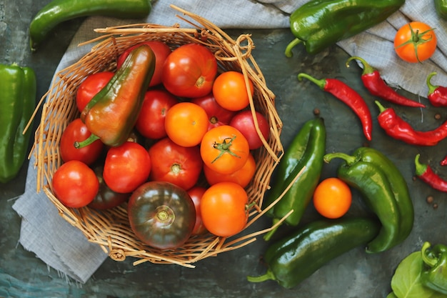 Panier avec des légumes naturels sur la table, tomates et poivrons mûrs, cuisine maison