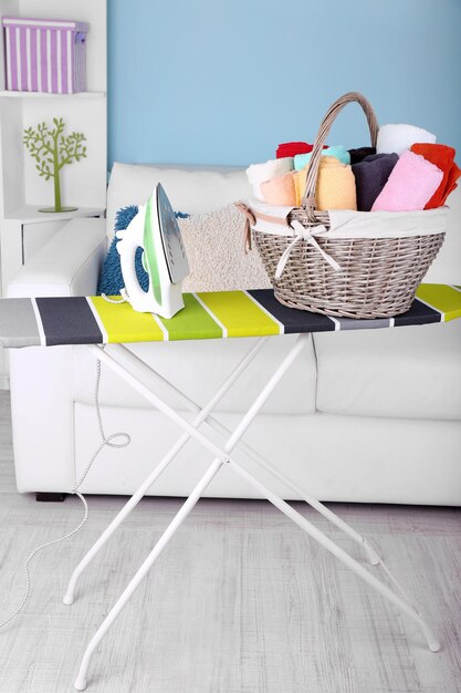 Photo panier avec linge et planche à repasser sur fond intérieur de maison