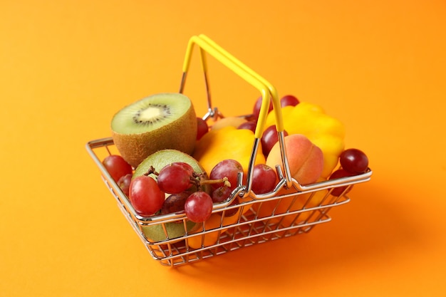 Panier de magasin avec des légumes et des fruits sur fond orange