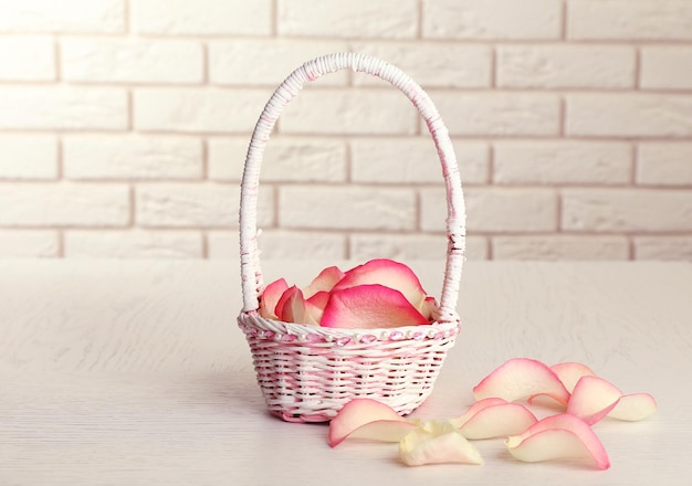 Panier de mariage avec pétales de roses sur table, sur fond clair