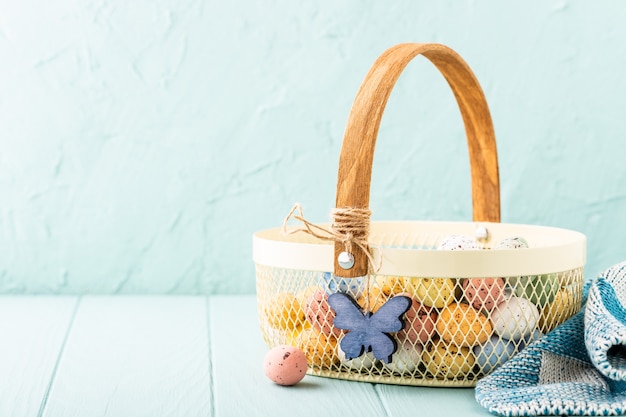 Panier en métal avec des oeufs de caille de Pâques colorés. Concept de vacances de printemps avec espace copie