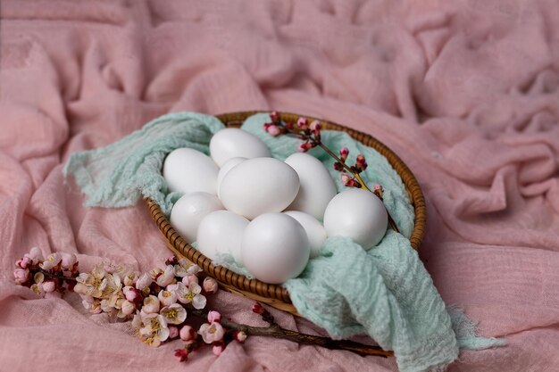 Un panier d'oeufs avec des fleurs sur une couverture rose