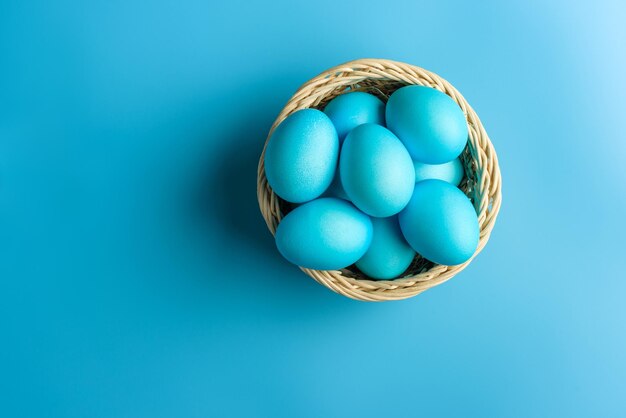 Panier avec des oeufs de Pâques bleus sur fond bleu avec espace de copie