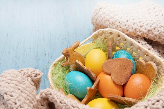 Panier avec des oeufs de Pâques colorés et des biscuits faits maison