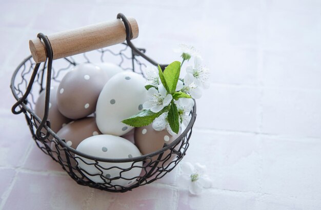 Un panier avec des oeufs de Pâques sur fond de carreaux roses