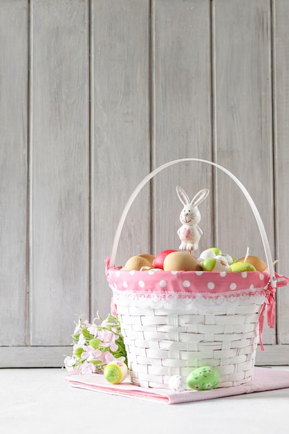 Panier d'oeufs de pâques avec un ruban rose et un panier blanc avec un lapin dessus.