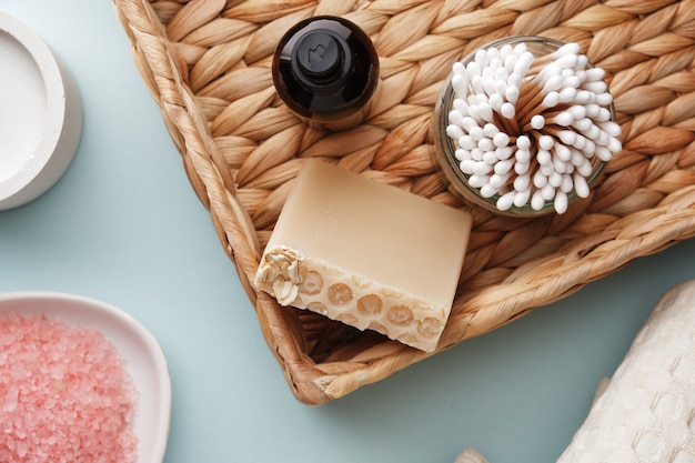 Le panier en osier contient du savon au miel fait à la main avec des cotons-tiges en bambou à l'avoine et un corps de bouteille en verre