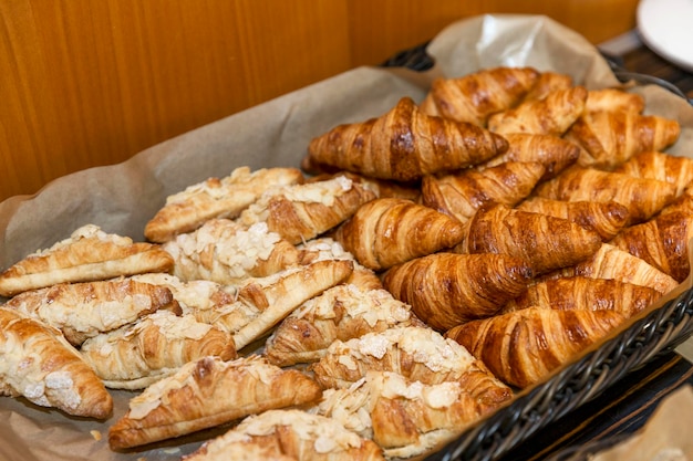 Panier en osier avec croissants frais sur la table du buffet Pâtisseries fraîches au petit-déjeuner pauses-café et réunions d'affaires Restauration lors d'événements Gros plan Vue de dessus Mise au point sélective