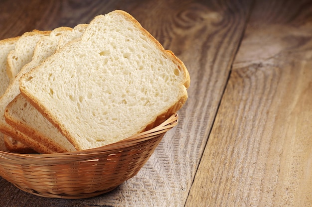 Panier en osier avec du pain grillé tranché sur une vieille table en bois