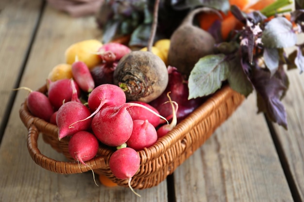 Panier en osier avec des légumes frais sur fond de bois