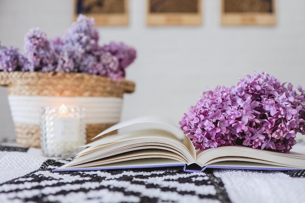 Panier en osier avec des lilas une bougie un livre ouvert sur la table Concept de bonjour