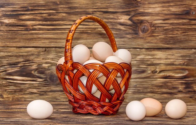 Panier en osier avec des oeufs sur fond en bois